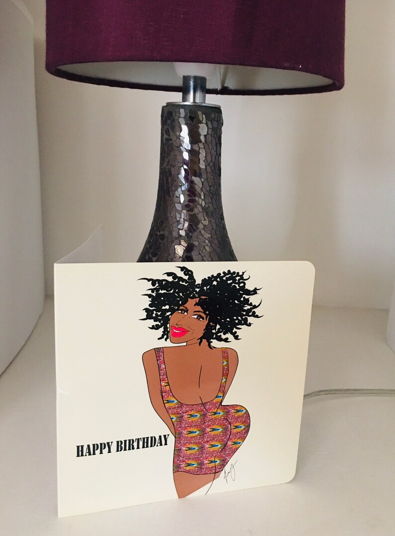May include: A birthday card featuring a cartoon illustration of a woman with curly black hair wearing a colorful patterned dress. The card has the text "HAPPY BIRTHDAY" printed on the bottom left corner.