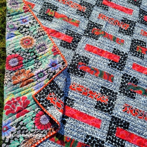 May include: A quilt with a black and white geometric pattern and red and white floral accents. The quilt is made with a variety of fabrics and textures. #EmilHansDesigns