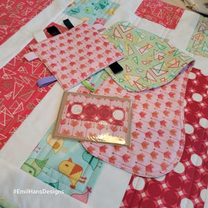 Tessuto Modern Tykes per trapunta per neonati con set regalo, bavaglino, giocattolo scricchiolante e biglietto d'auguri. Verde menta e rosso. La trapunta misura 112 x 137 cm.