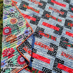 Puede incluir: Una colcha con un patrón geométrico en blanco y negro y acentos florales rojos y blancos. La colcha está hecha con una variedad de telas y texturas. #EmilHansDesigns