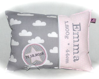 Op de afbeelding: Een gepersonaliseerd babykussen met een grijs wolkenpatroon en roze stippen. Het toont de naam "Emma", gewicht 1.800g en afmeting 44cm. Een ster-vormig embleem toont de datum 17.12.2018.