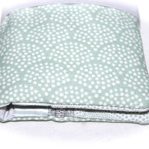 May include: A green zippered pouch with a white polka dot pattern. The pouch is folded and the zipper is visible.