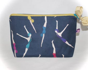 Peut inclure: Trousse de maquillage bleu marine avec un motif répété de nageurs de différentes couleurs. La trousse a une fermeture éclair jaune et un nœud vichy. Une petite étiquette rose est également attachée.