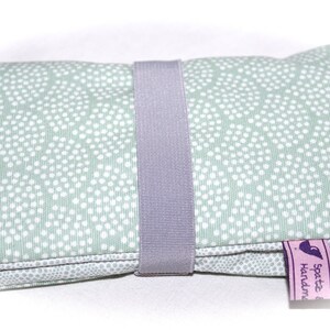 May include: A light green zippered pouch with a white polka dot pattern. The pouch has a gray fabric strap and a purple tag that says "Spatz & Handmade".