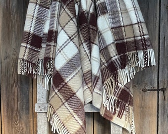 May include: A brown, beige, and white plaid throw blanket with fringe hanging on a wooden ladder.