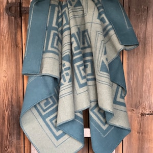 Peut inclure: Une couverture à motifs bleus et verts avec un motif géométrique est pliée et drapée sur une échelle en bois.