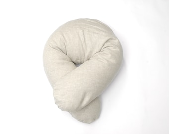 May include: A beige, U-shaped pregnancy pillow with a soft, textured fabric.