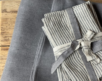 May include: A set of gray linen kitchen towels with white stripes. The towels are folded and tied together with a gray ribbon.