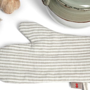 May include: A striped beige and white oven mitt with a hanging loop. The mitt is made of a soft, textured fabric.