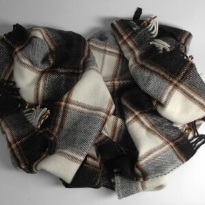 May include: A black, white and brown plaid throw blanket with fringe on the edges.