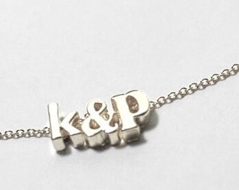 Può includere: Una collana a catena d'argento con un ciondolo che dice "K&P".