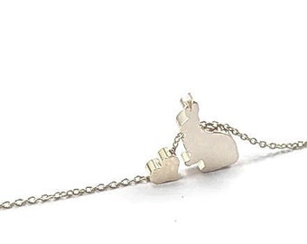 May include: A silver chain necklace with a small heart charm and a larger rabbit charm.