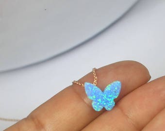 May include: A delicate silver chain necklace with a blue opal butterfly pendant. The butterfly is iridescent and has a sparkly finish.