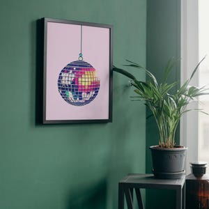May include: A framed print of a colourful disco ball hanging from the ceiling against a pink background.