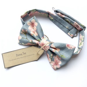 Mens cherry blosom bow tie, in bluey grey linen with a pink floral print.