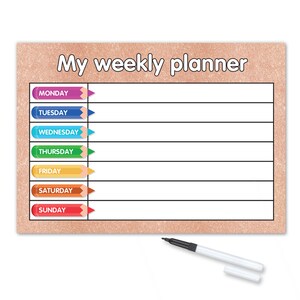 Pode incluir: Um quadro branco de apagamento a seco com um fundo de glitter rosa. O quadro tem o texto "My weekly planner" no topo e uma lista dos dias da semana com lápis de cor ao lado de cada dia. O quadro vem com um marcador de apagamento a seco preto.