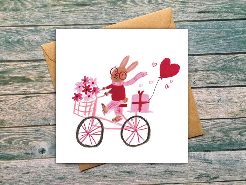 May include: A pink bicycle with a basket of pink flowers, a pink gift box, and a red heart balloon. A brown rabbit with red glasses and a pink scarf is riding the bicycle.
