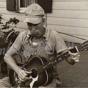 Könnte beinhalten: Ein Mann in einem gestreiften Hemd und einer Mütze spielt eine braune Akustikgitarre. Er hält ein Mundharmonika im Mund.