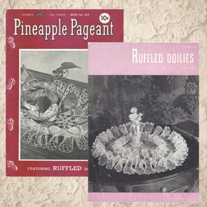 Op de afbeelding: Twee vintage haakpatroonboekjes. Het rode boekje heet "Pineapple Pageant" met ananas illustraties. Het roze boekje heet "Ruffled Doilies". Beide bevatten gedetailleerde haakontwerpen.