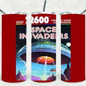 May include: A red tumbler featuring the Atari 2600 Space Invaders video game cartridge design. The design includes the game's logo, a spaceship, and a retro space scene. The tumbler has a silver straw and lid.