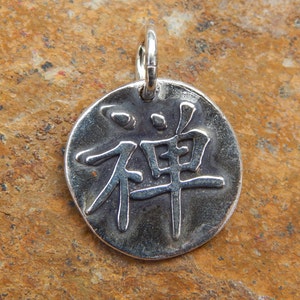 May include: Silver pendant with the Chinese character for "Zen" embossed on it.