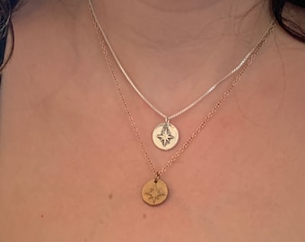 May include: Two gold necklaces with star-shaped pendants. The top necklace is silver and the bottom necklace is gold.