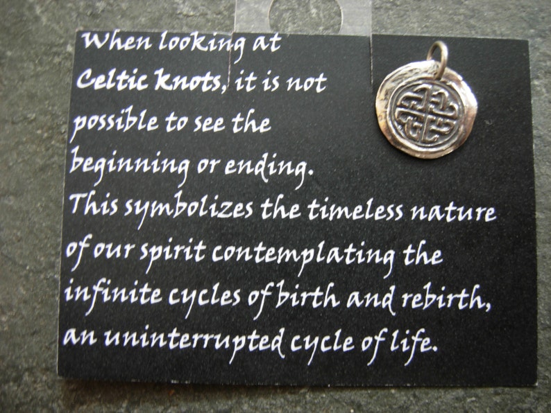 May include: A silver Celtic knot charm pendant with a black card that reads: "When looking at Celtic knots, it is not possible to see the beginning or ending. This symbolizes the timeless nature of our spirit contemplating the infinite cycles of birth and rebirth, an uninterrupted cycle of life."