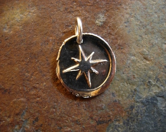 May include: A silver pendant featuring a compass rose design. The circular pendant has a raised edge and a loop for a chain. The compass rose, with eight points, is set against a dark backdrop.