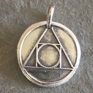 May include: Silver pendant with a circle inside a triangle design.