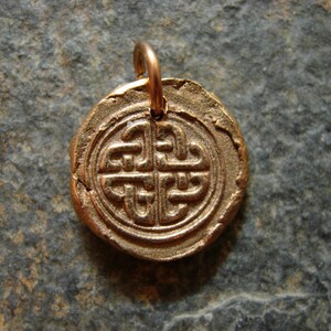 May include: A gold-coloured pendant featuring a Celtic knot design. The pendant is round and has a loop at the top for attaching a chain.