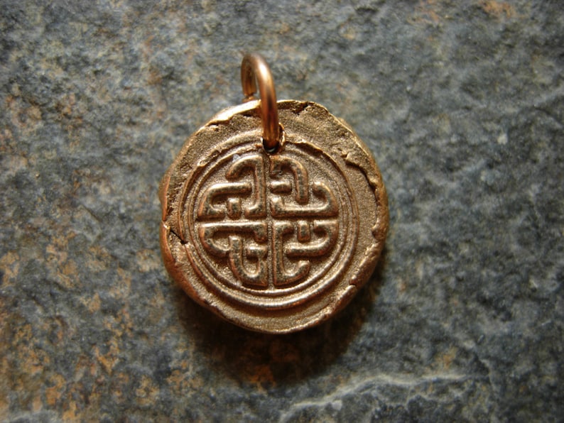 May include: A gold-coloured pendant featuring a Celtic knot design. The pendant is round and has a loop at the top for attaching a chain.