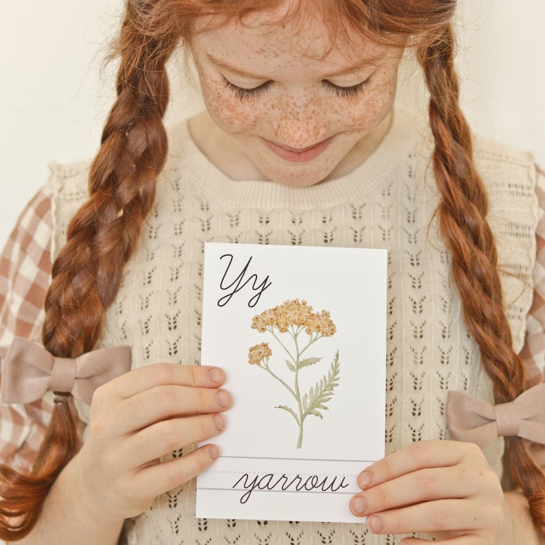 Pu&ograve; includere: Un cartoncino bianco con la lettera Y e la parola "yarrow" scritta in corsivo. Un'illustrazione ad acquerello di una pianta di achillea con fiori gialli &egrave; sul cartoncino.