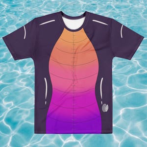 May include: A purple t-shirt with a gradient design that transitions from orange to pink to purple. The design resembles a dragon's chest and belly. White accents are on the sleeves and shoulders. A small, gray, circular emblem is on the lower right.
