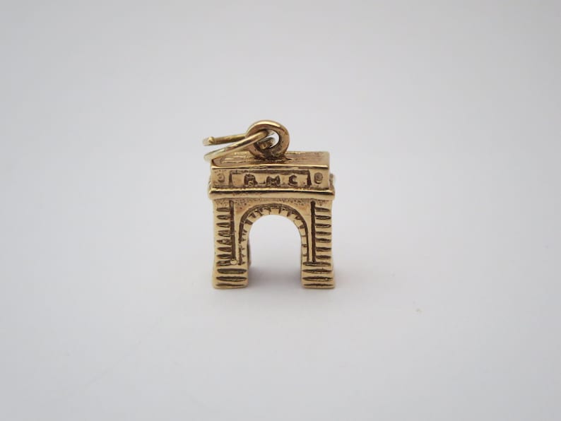 Puede incluir: Encanto de color dorado con forma de Arco del Triunfo en Par&iacute;s, Francia. El encanto tiene un bucle en la parte superior para sujetarlo a un collar o pulsera.