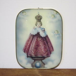 Peut inclure: Une image encadr&eacute;e d'une figure religieuse, un jeune gar&ccedil;on portant une couronne et une robe rouge, tenant un globe. L'image est entour&eacute;e d'anges et porte le mot "THIS" en bas.