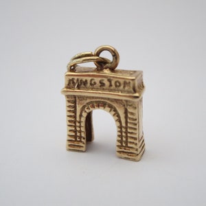 Puede incluir: Encanto de oro en forma de arco de Kingston, Nueva York. El encanto tiene la palabra "Kingston" inscrita en la parte superior.