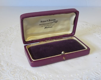 May include: A purple velvet-lined jewelry box with a hinged lid. The inside of the lid has a label that reads "Eades & Brossette Limited The Downtown Jewellers 27 McGill Street Montreal".
