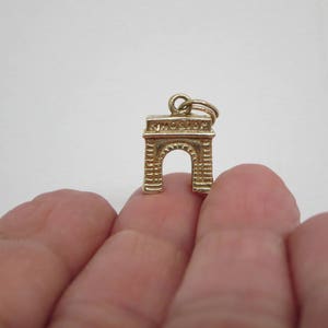 Puede incluir: Encanto de oro en forma del Arco del Triunfo, un monumento famoso en Par&iacute;s, Francia.