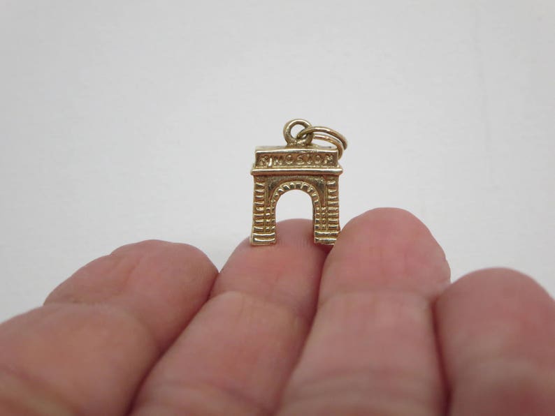 Puede incluir: Encanto de oro en forma del Arco del Triunfo, un monumento famoso en Par&iacute;s, Francia.