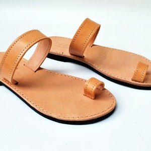 Peut inclure: Paire de sandales en cuir marron clair avec une boucle d'orteil et une bride sur le dessus du pied. Les sandales ont une semelle noire et sont pr&eacute;sent&eacute;es sur fond blanc. Taille 37 (environ 23,5 cm).