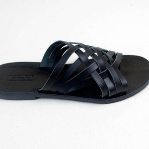 Puede incluir: Sandalias de cuero negro con un dise&ntilde;o de correas trenzadas. Las sandalias tienen una suela plana y un estilo sencillo y elegante. El dise&ntilde;o de punta abierta es ideal para el clima c&aacute;lido.