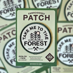 May include: Embroidered iron-on or sew patch with a green border and white background. The patch features a stylised image of a forest with a sun and the text "Take Me To The Forest" in black. The text "You Don't Have To Go Far, To Be Somewhere Else" is printed in smaller text below the patch.