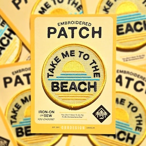 May include: Embroidered iron-on or sew patch with a yellow background and blue and white waves. The patch says "Take Me To The Beach" with a yellow sun setting over the waves. The text "You Don't Have To Go Far To Be Somewhere Else" is printed below the patch.