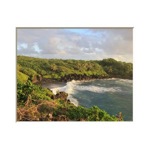 Puede incluir: Una vista panorámica de una playa de arena negra con agua turquesa y olas blancas rompiendo en la orilla. Una exuberante vegetación verde cubre los acantilados rocosos que rodean la playa.