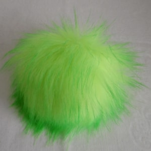 Könnte beinhalten: Ein leuchtend neongrüner Kunstfell-Pompon. Der runde Pompon hat eine flauschige Textur mit langen, weichen Strähnen. Die Farbe ist ein leuchtender, auffälliger Grünton, perfekt für Bastelprojekte oder Accessoires.