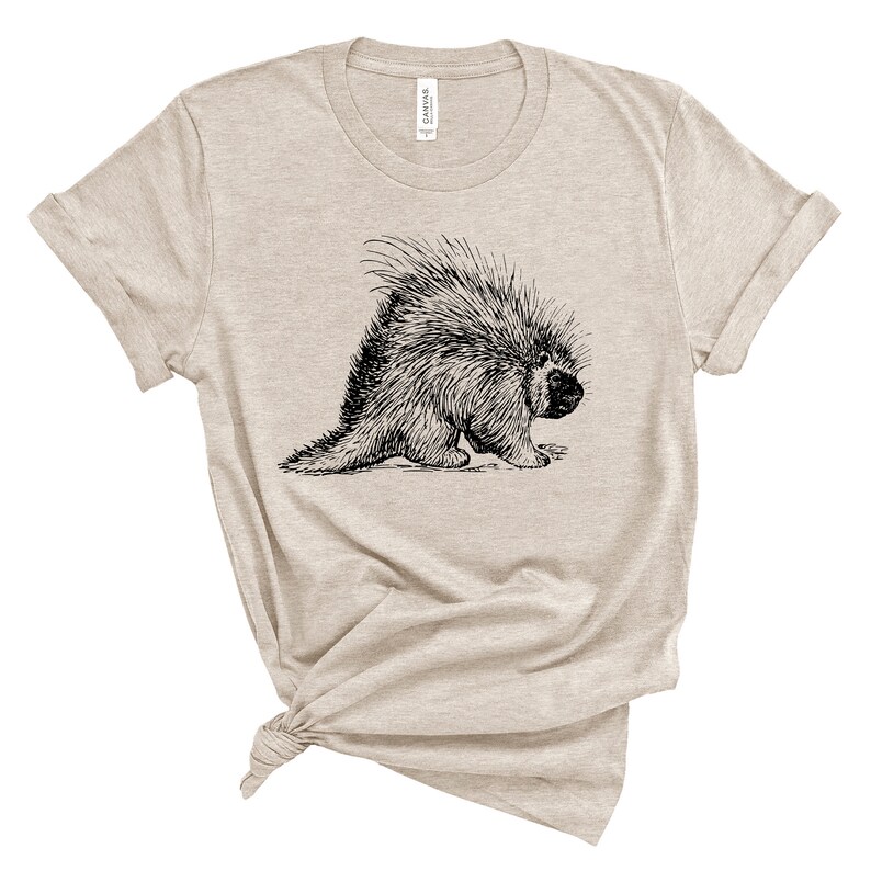K&ouml;nnte beinhalten: Ein beiges T-Shirt mit einer Schwarzwei&szlig;illustration eines Stachelschweins.