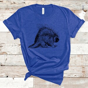 K&ouml;nnte beinhalten: Ein k&ouml;nigsblaues T-Shirt mit einer Schwarz-Wei&szlig;-Zeichnung eines Stachelschweins auf der Vorderseite.