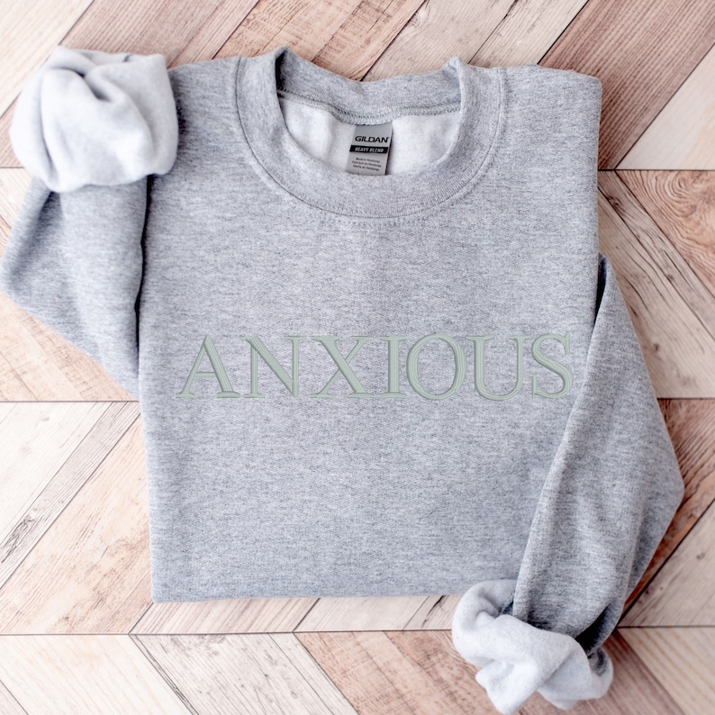 May include: Gray sweatshirt with the word "ANXIOUS" printed in green on the front.