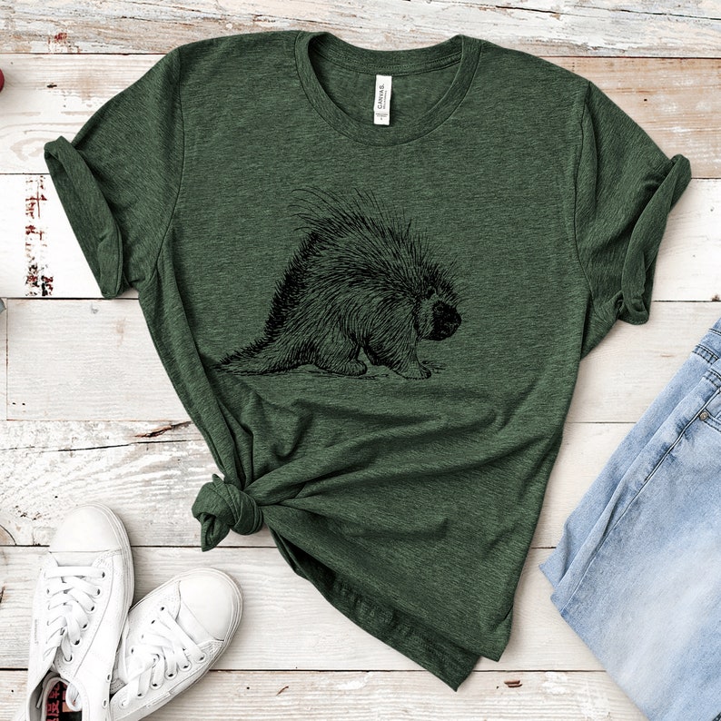 K&ouml;nnte beinhalten: Ein gr&uuml;nes T-Shirt mit einer schwarz-wei&szlig;en Illustration eines Stachelschweins auf der Vorderseite.