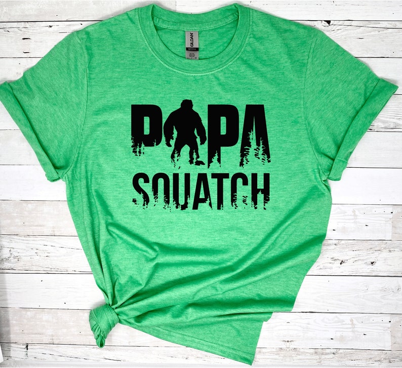 May include: Green t-shirt with a black graphic of a Bigfoot silhouette and the text "Papa Squatch".